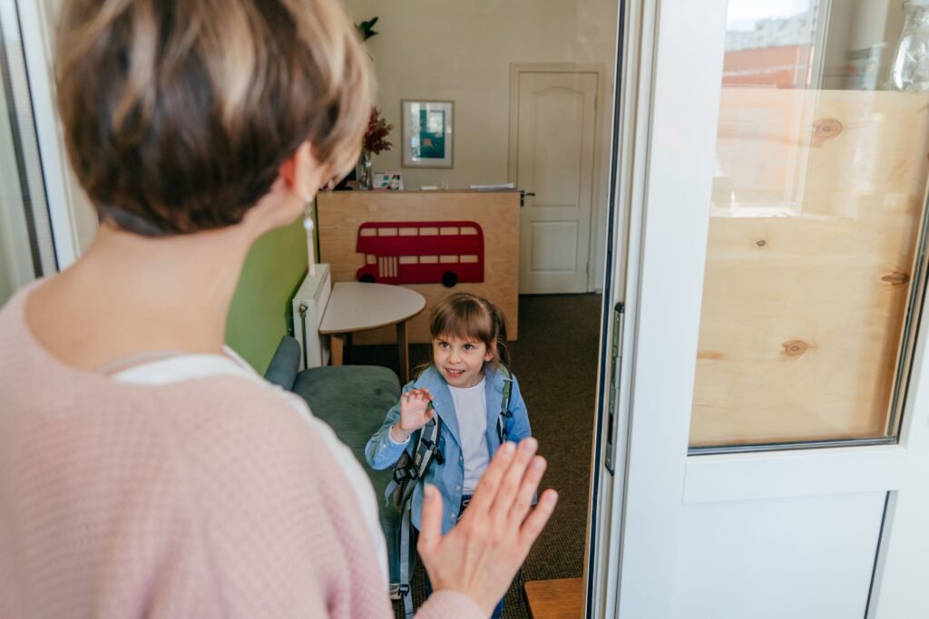 Kind mit Rucksack winkt zur Begrüßung in einer Einrichtung für Kinderbetreuung in Herne